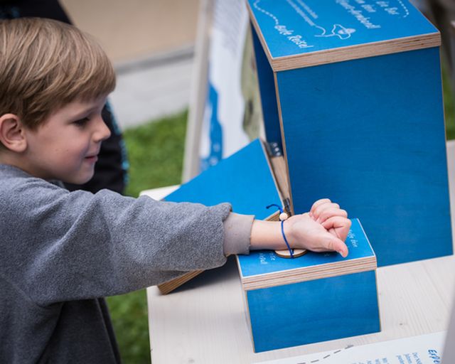 Kind scannt Armband an Ausstellung ein